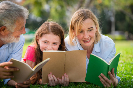小女孩和父母一起在户外花园学习. 教育和家庭生活方式.照片