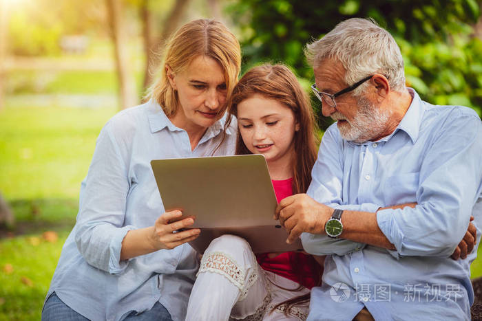 快乐的一家人在花园公园一起使用笔记本电脑儿童教育和家庭活动理念
