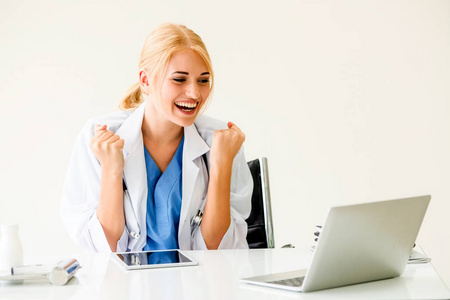 快乐成功的女医生在医院或医疗机构感到愉快，同时在办公室工作报告。 成功的概念。