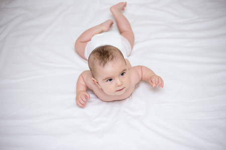 一个小可爱的婴儿正在白色的床上爬行