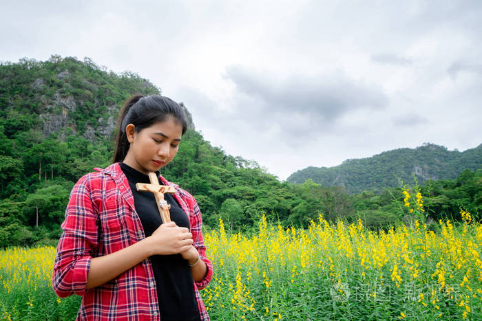 年轻漂亮的女人在大自然的背景下祈祷希望和信仰的概念