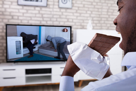 观看电视时吃巧克力的非洲人的特写