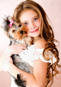 可爱的微笑的小女孩抱着小狗约克郡猎犬玩耍