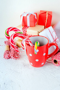带有棉花糖和糖果棒的红色杯子，白色背景上有许多礼物。卡片假日概念。复制空间，