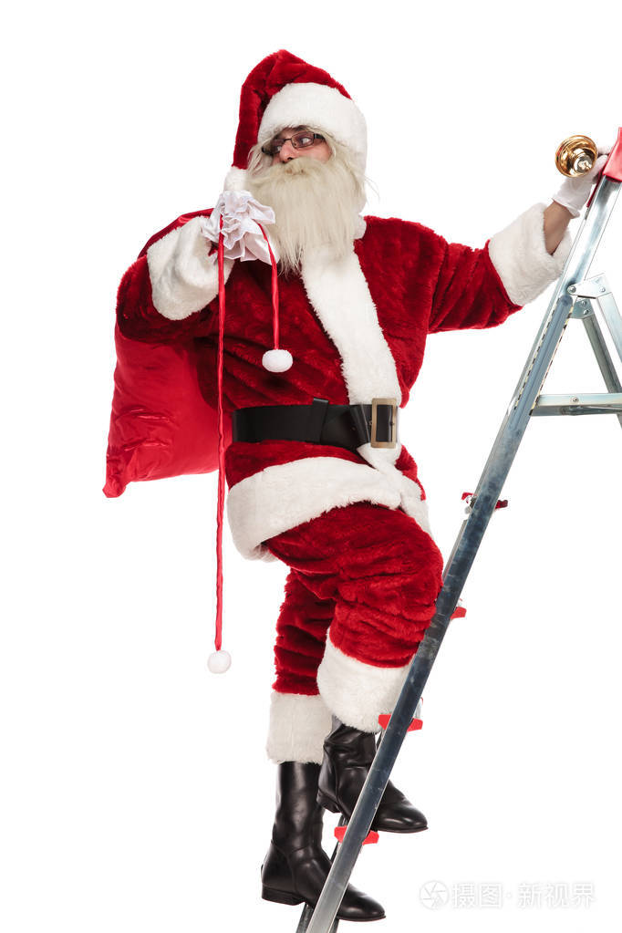 站在梯子上的圣诞老人的侧视在白色背景下看着后面全身照片