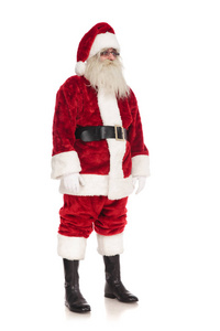 圣诞老人戴着眼镜站在白色的背景上，看着侧面的全身照片