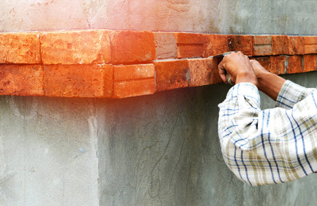 在墙上安装砖块工人在施工现场用水泥安装红砖石膏
