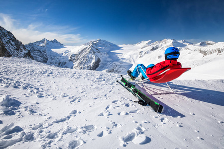 年轻快乐，迷人的滑雪者坐在山顶上，欣赏来自意大利普雷塞纳冰川的景色。