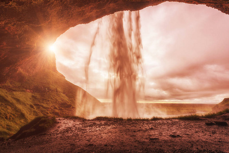 美丽的塞尔贾兰斯佛斯瀑布，阳光明媚的秋天景观，从冰岛南部的小洞穴观看。