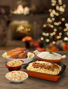 餐桌上有烤鸡，腊肉，意大利面，米饭和蛋黄酱，有圣诞背景。