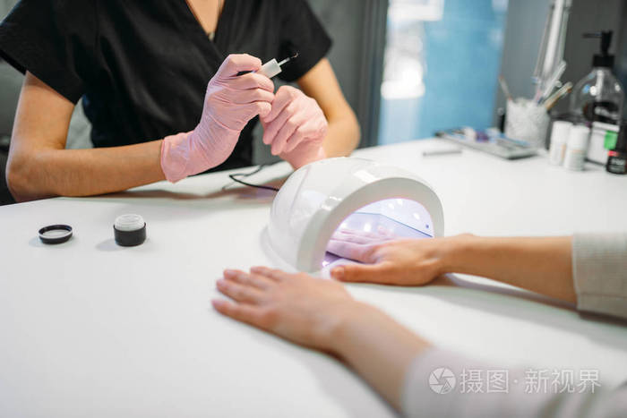 女客户在背景美容院用粉红色手套在吹风机美容师中烘干凝胶清漆 美甲师做手部护理美容手术照片 正版商用图片14tw54 摄图新视界 女客户在背景美容院用粉红色手套在吹风机美容师中烘干凝胶清漆 美甲师做手部护理美容手术照片 正版商用图片14tw54 摄图新视界