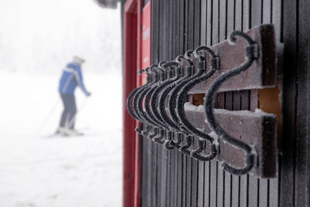 房子的棕色木墙上覆盖着霜冻的铁黑色滑雪板和滑雪板钩子