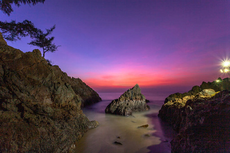 在普吉岛香蕉海滩日落时，海浪撞击了石角中部的大锥形岩石