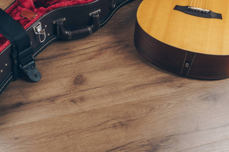 木制地板上有黑色腰带的吉他和皮吉他硬壳