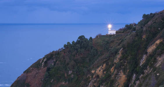 伊盖尔多山灯塔中的光与海洋在背景城市多诺斯蒂亚伊斯卡迪