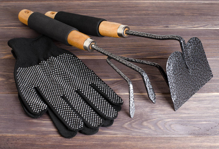 花园工具和尼龙手套。 木制背景