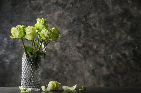 花瓶，桌上放着美丽的绿玫瑰花束，背景是肮脏的