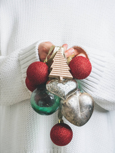 女人穿着温暖的毛衣，手里拿着老式的圣诞树玩具，孤立在白色的背景上。 新年概念模拟