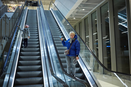 母亲和孩子一起在自动扶梯背景上。航站楼, 机场旅游, 关爱