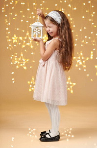 女孩在圣诞灯中摆灯笼黄色背景粉色连衣裙