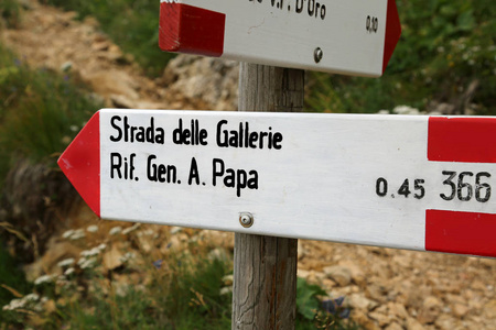 带有意大利在山区位置文本的小径标记。 横跨德尔盖莱，意思是隧道的道路