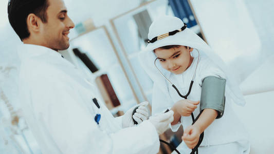 阿拉伯男性医生检查血压男孩。 儿科医生的孩子。 医院概念。 健康的概念。 儿童病人出诊医生。 医生检查血压。 接待治疗师。