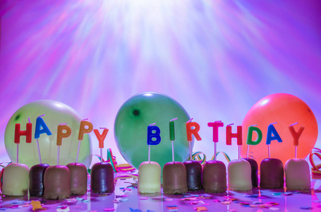 彩色燃烧的生日蜡烛和小巧克力糖果，气球和纸屑
