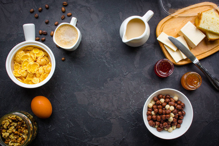 玉米片咖啡，干酪，面包，黄油，鸡蛋，果酱和其他成分，早餐在黑暗的背景下。 顶部视图，复制空间