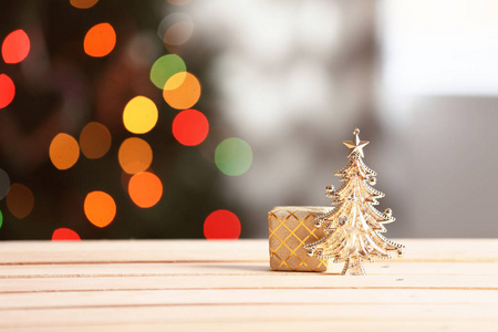 木制桌子上的礼品盒贴在模糊的圣诞树上