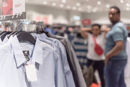 选择性聚焦浅D OF形象的服装店与时尚服装衣架和模糊的客户购物选择纺织品背景。