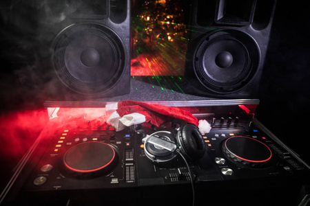 带耳机的DJ混音机在黑暗的夜总会背景与圣诞树除夕。在Dj表上关闭新年元素的视图。假日派对的概念。空的空间