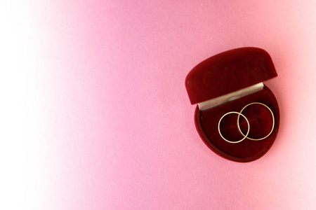 一个美丽的红色节日礼品盒天鹅绒为两个订婚, 结婚戒指与珍贵的黄金轮珍贵的桩戒指。理念 求婚婚约订婚