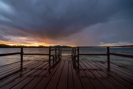 夜晚的暴风雨在湖的天空中反射出潮湿的木板，木制码头