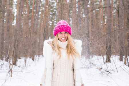 时尚和人的概念在冬季雪公园穿着白色外套和粉红色帽子的迷人的年轻金发碧眼的妇女的肖像