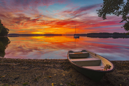 在美丽的日落中，木桥旁的小船在湖上
