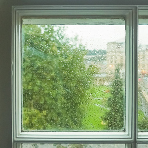 潮湿的窗玻璃,有雨水,水滴和绿色背景照片