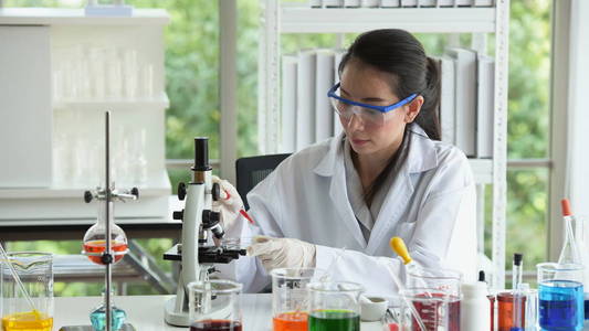 年轻的女科学家正在亚洲实验室在实验室里拿着试管的科学家