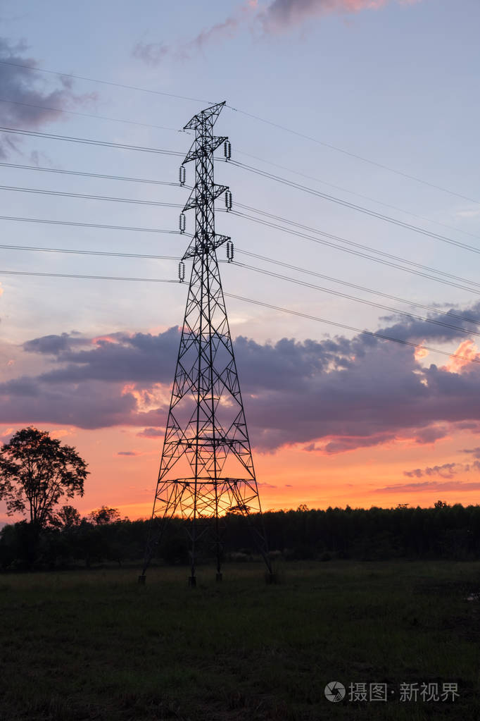 高压电力传输塔形轮廓与发电厂对暗灯天空.