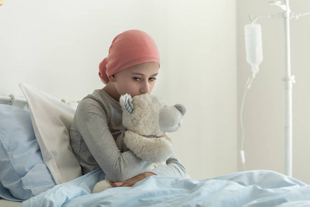 体弱多病的女孩，头巾抱着泰迪，旁边滴在医疗中心