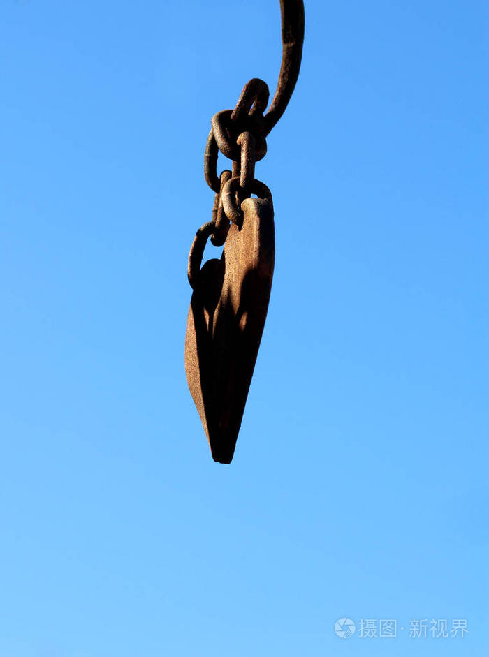 一颗古老的金属心,铁链环悬在蓝天上.