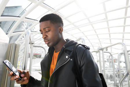 美国黑人年轻人在车站看手机的画像