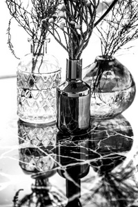 大理石桌子上有花的玻璃花瓶。 玻璃花瓶的黑白图像。