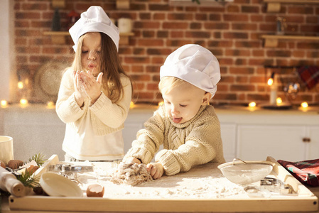 幸福的家庭有趣的孩子们正在准备面团，在厨房里玩面粉