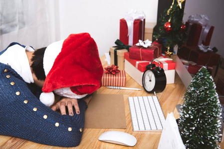 圣诞晚会和新年快乐后，带圣诞帽的商务女性睡在办公桌上。