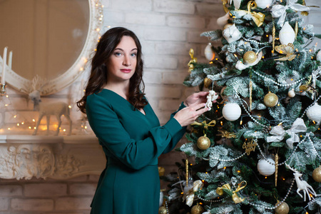 一中壁炉旁的圣诞树上装饰着一位身穿绿色连衣裙的美女