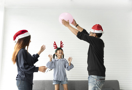 亚洲家庭的母亲和父亲和女儿一起在家的客厅里过着快乐的圣诞节。