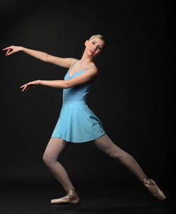 美丽的年轻金发碧眼的芭蕾舞女演员在黑色的背景上跳舞