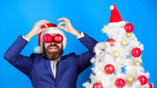 圣诞节的乐趣。商业和圣诞节的概念。圣诞老人举行圣诞舞会装饰。假期是为了好玩。男人留胡子的嬉皮士穿着正式的西装和圣诞老人的帽子。商