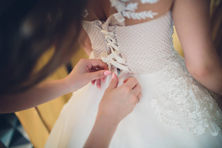伴娘绑在新娘优雅的婚纱上的弓