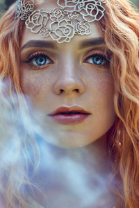 美丽的红头挪威女孩，大眼睛和雀斑的脸在森林里。红发女人在大自然中特写的肖像，令人难以置信的神秘外观，长长的波浪红色头发在阳光下。